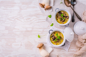 Delicious mushroom soup in serving pot on wooden table