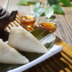Closeup of glutinous rice zongzi and refreshments in a white porcelain plate, traditional Chinese cuisine
