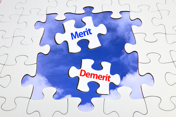 Fototapeta premium 青空背景とジグソーパズルのピースに描かれたMeritとDemeritの文字