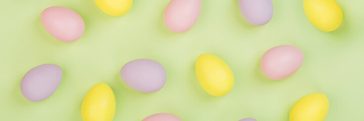 Stylish background with colorful easter eggs pastel colors isolated on green background. Horizontal long banner for web design. Flat lay, top view, mockup, overhead, template