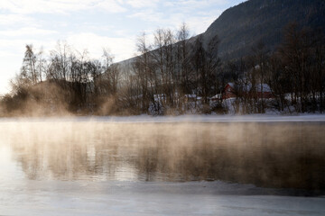 Fototapeta na wymiar The river is about to freeze. It is very cold and the river is much warmer than the air, therefore the smoke or the damp from the river. Shot at Gol, Norway in February. Minus 20 degreases Celsius. 