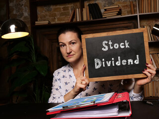 High resolution hand holding white card with written text Stock Dividend - closeup shot.