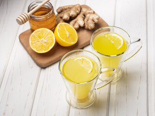 Two glass cup of lemon ginger lemonade and ingredients on cutting board