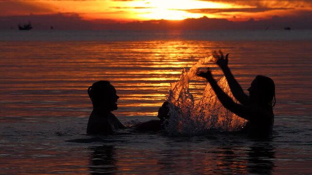 Happy family swims at sea at sumset on tropical beach. Enjoying on vacation