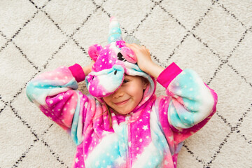 Cute girl in pink kigurumi unicorn pyjamas costume