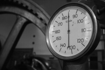 Old tachometer on a very old steam machine. Black and white photo.