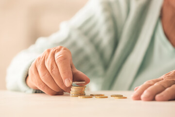 Senior woman counting coins on table. Concept of pension - obrazy, fototapety, plakaty