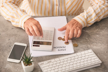 Senior woman calculating expenses at table. Concept of pension - obrazy, fototapety, plakaty