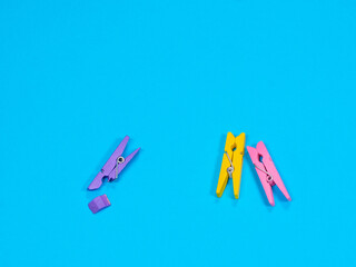Spring-type wooden violet clothespin with fracture leg on blue background. Bullying, loneliness and depression concept. Copyspace for text. Deride or laugh, mock