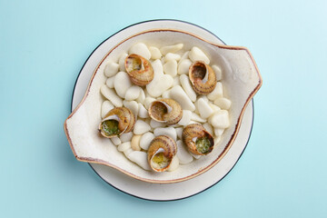 Escargots de Bourgogne. Fried snails with garlic butter, gourmet dish, in traditional ceramic plate.