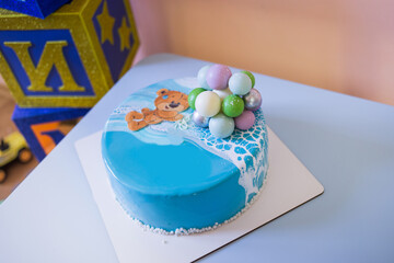 
A blue cake with a bear and balls on the background of a children's holiday - birthday.