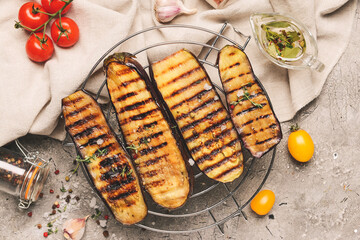 Cooling rack with tasty grilled eggplant on grunge background