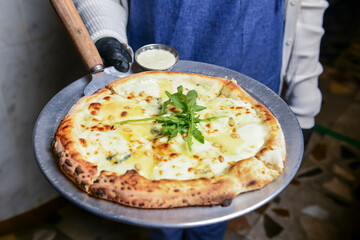 Waiter serving pizza Margherita in restaurant or diner, eating out concept, waiter at work. Fast food, junk food concept