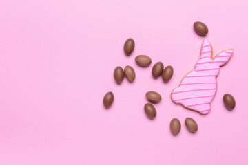 Tasty chocolate eggs and Easter cookie on color background