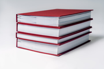 Stack of red hardcover books or reports on white background. Copy space.