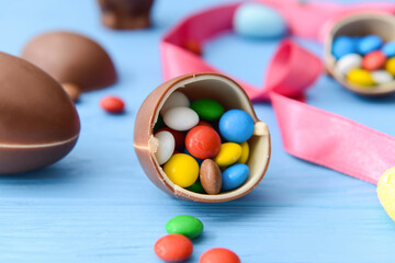 Fototapeta na wymiar Tasty chocolate eggs and candies on color wooden background