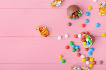 Tasty chocolate egg and candies on color wooden background