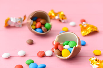 Tasty chocolate egg and candies on color wooden background