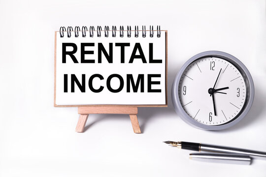 rental income, text on white notepad paper on white background. near the table clock
