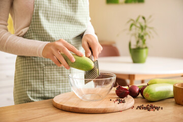 Woman grating zucchini in kitchen