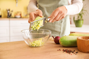 Woman grating zucchini in kitchen