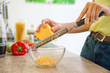 Woman grating cheese in kitchen
