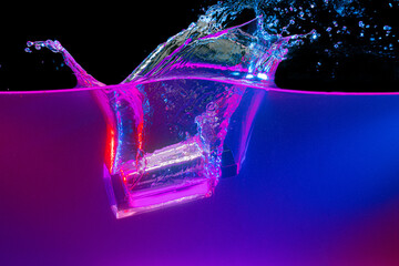 Perfume bottle diving into the water with a splash in neon light
