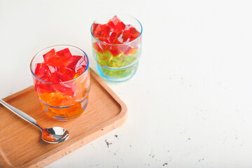 Glasses with tasty jelly cubes on white background