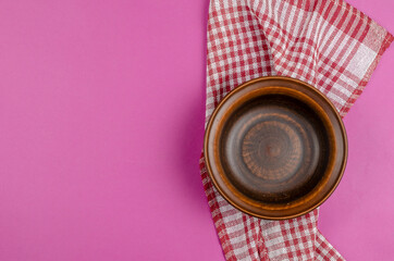 An empty bowl of red clay on a pink background.