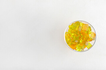 Glass bowl with tasty jelly cubes on white background