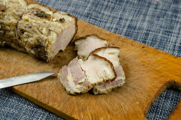 Traditional Ukrainian dish. Baked pork belly with spices on a wooden cutting board.