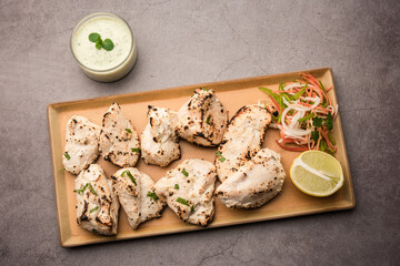 Chicken Malai Tikka or Indian Chicken Kebab in a Plate with Green Mint Chutney and salad
