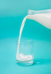 Milk pouring in a glass isolated on blue background.