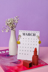 Calendar with female accessories, flowers and fashion magazine on color background. International Women's Day celebration
