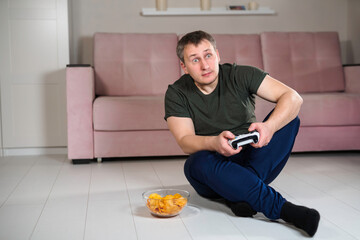 young man with a joystick in his hands, a tense expression on his face, plays a video game