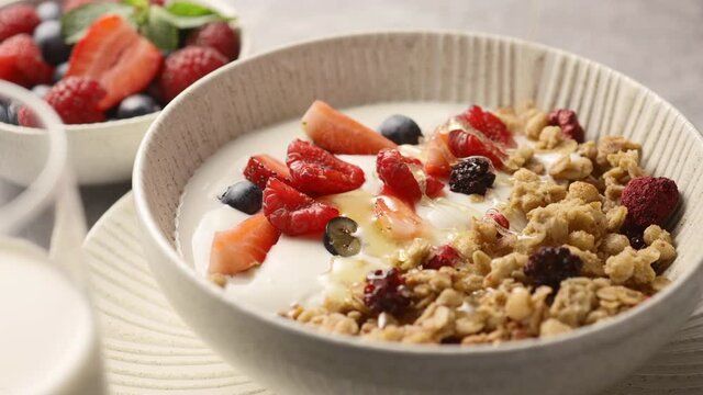Granola with yogurt and berries poured with honey, close-up, breakfast 