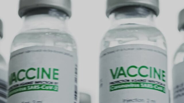 Flacons of vaccine for COVID-19 coronavirus cure are rotated quickly and then slowly in research lab. Vaccination injection clinical trial during pandemic. Bottles are slowly spinning clockwise. Macro