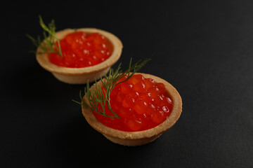 Tartlets with caviar on black background, close up