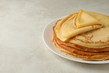 Plate with thin pancakes on white textured background