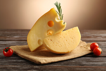 Maasdam cheese and cream cheese with walnuts, decorated with a sprig of rosemary and cherry tomatoes, on a wooden table.