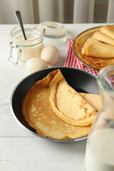 Concept of tasty breakfast with thin pancakes on white wooden table