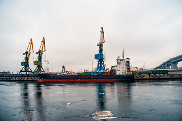  View on the sea port with gantry cranes and berthed cargo ships. Cranes in cargo port of St. Petersburg in winter time