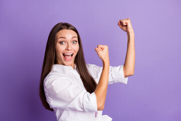 Photo portrait of excited girl with raised fists ready to fight isolated on vivid purple colored background