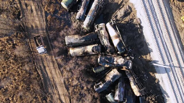 A train wreck on the railroad, scattered cisterns, worth a dump truck. Aerial view of the accident - a crash with damaged wagons lying next to the rails. Rescuers carry out repair work.