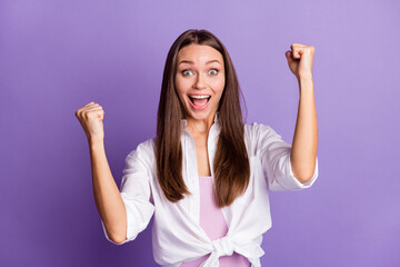 Photo portrait of cheerful woman raising fists celebrating isolated on vivid purple colored background