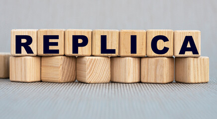 REPLICA - words on wooden bars on cubes on a gray background
