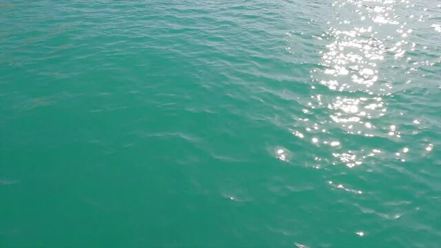 Bright shiny sun glare reflection on deep blue sea water surface n calm cyan ocean wave or ripple in tropical summer or spring sunlight n sunray in sunny day, 4k cinemagraphs b-roll video footage