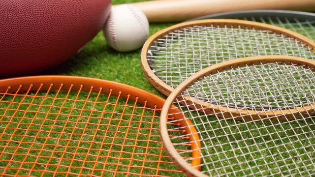 Sport equipment; rackets, balls and baseball bat on grass