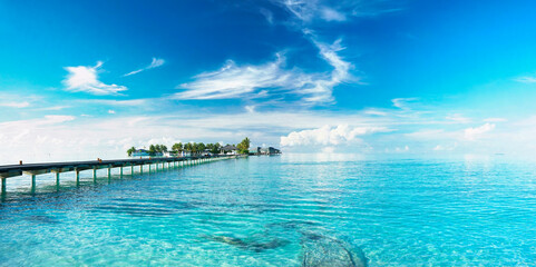 Beautiful landscape with bridge to pier. Color fusion of ocean and sky. Light ripples on amazingly clear water. Perspective receding into distance. Image fine vacation on summer. Relax and rest. - obrazy, fototapety, plakaty