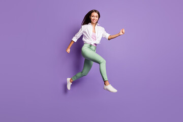 Fototapeta na wymiar Full length photo of active energetic girl jump run wear pants sneakers white shirt isolated violet color background
